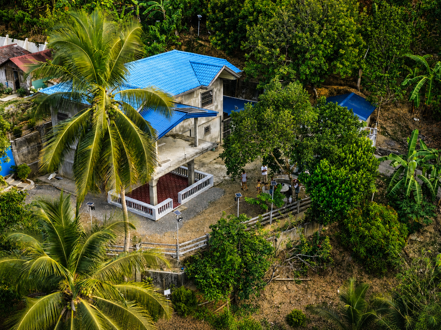 Aerial view of the two-storey house with blue roof and tropical trees in Dulangan, Puerto Galera